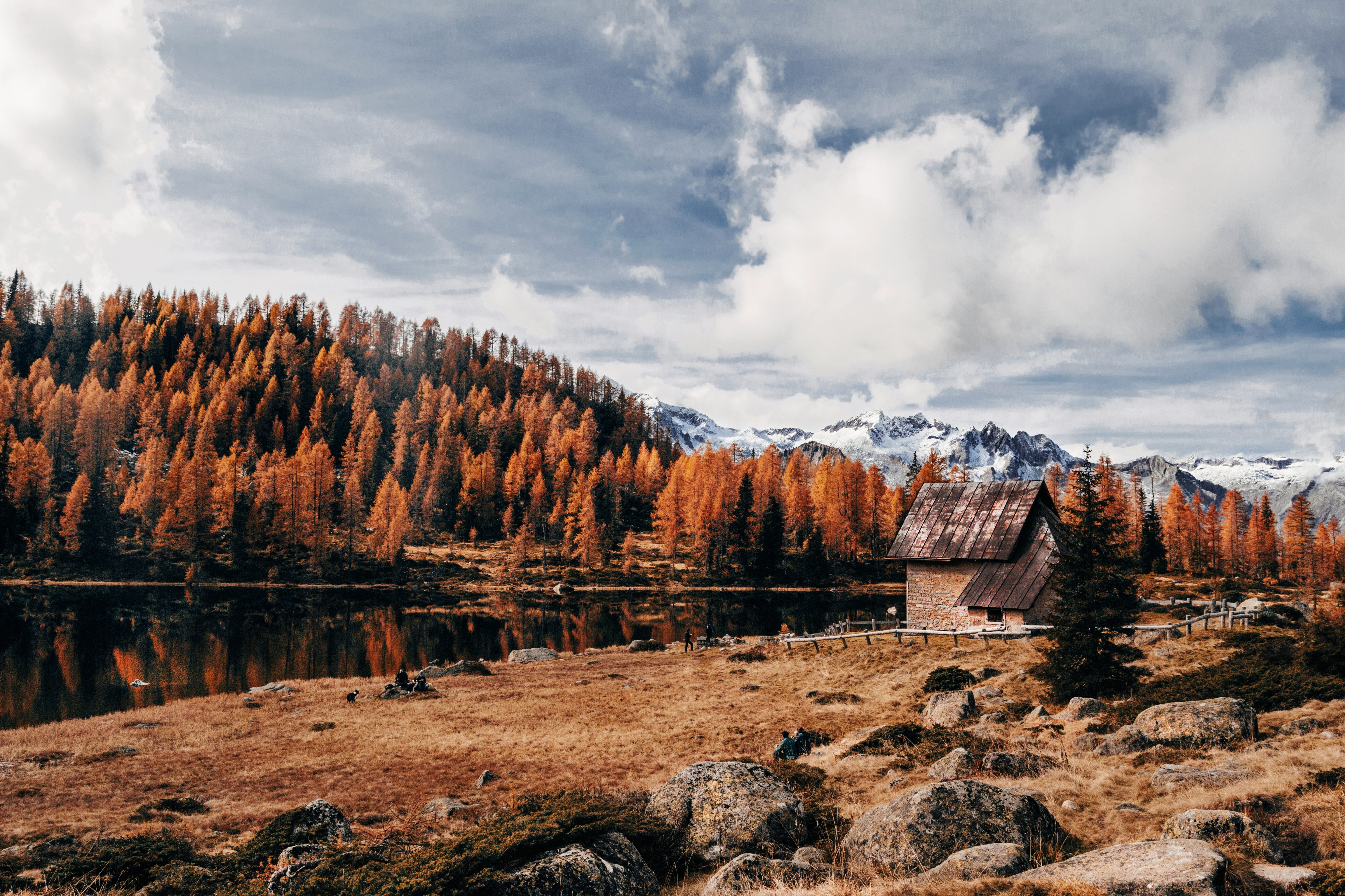 brown wooden house near brown mountain under white clouds during daytime